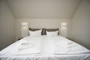 A neatly made double bed with white linens and two pillows, flanked by wall-mounted light fixtures. - Close to the beach with a balcony; access to the pool and sauna - Strandhaus Mönchgut FeWo11 (Middelhagen)