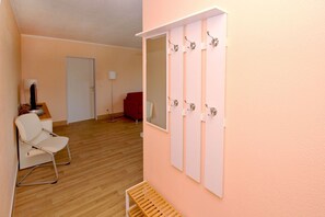 A room with a wooden floor, a white chair, a red sofa, and a wall-mounted mirror with hooks. - Close to the beach with a balcony; access to the pool and sauna - Strandhaus Mönchgut FeWo12 (Middelhagen)