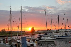 A marina with multiple sailboats docked, a sunset in the background, and a calm water surface. - Close to the beach with balcony, use of swimming pool and sauna - Strandhaus Mönchgut FeWo12 (Middelhagen)
