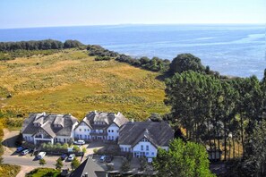 A coastal property with a large house and a smaller building, surrounded by greenery and a view of the sea. - 2-room vacation apartment near the beach with balcony - Strandhaus Mönchgut FeWo 10 - (Middelhagen)