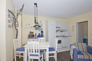 Un espace de vie compact comprenant un coin repas, une kitchenette et un canapé.