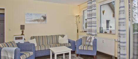 A living room with a sofa set, a coffee table, and a radiator.