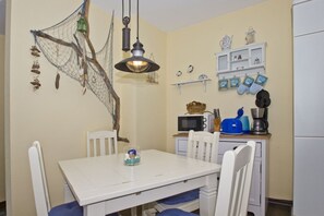 A small kitchen with white cabinets, a microwave, a coffee maker, and a hanging light fixture.