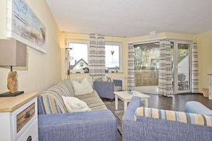 A cozy living room with striped sofas, a small table, and a view of a house through the window.