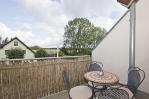 A balcony with a table and chairs, a view of houses, and a wooden fence. - 2-room vacation apartment near the beach with balcony - Strandhaus Mönchgut FeWo 10 - (Middelhagen)