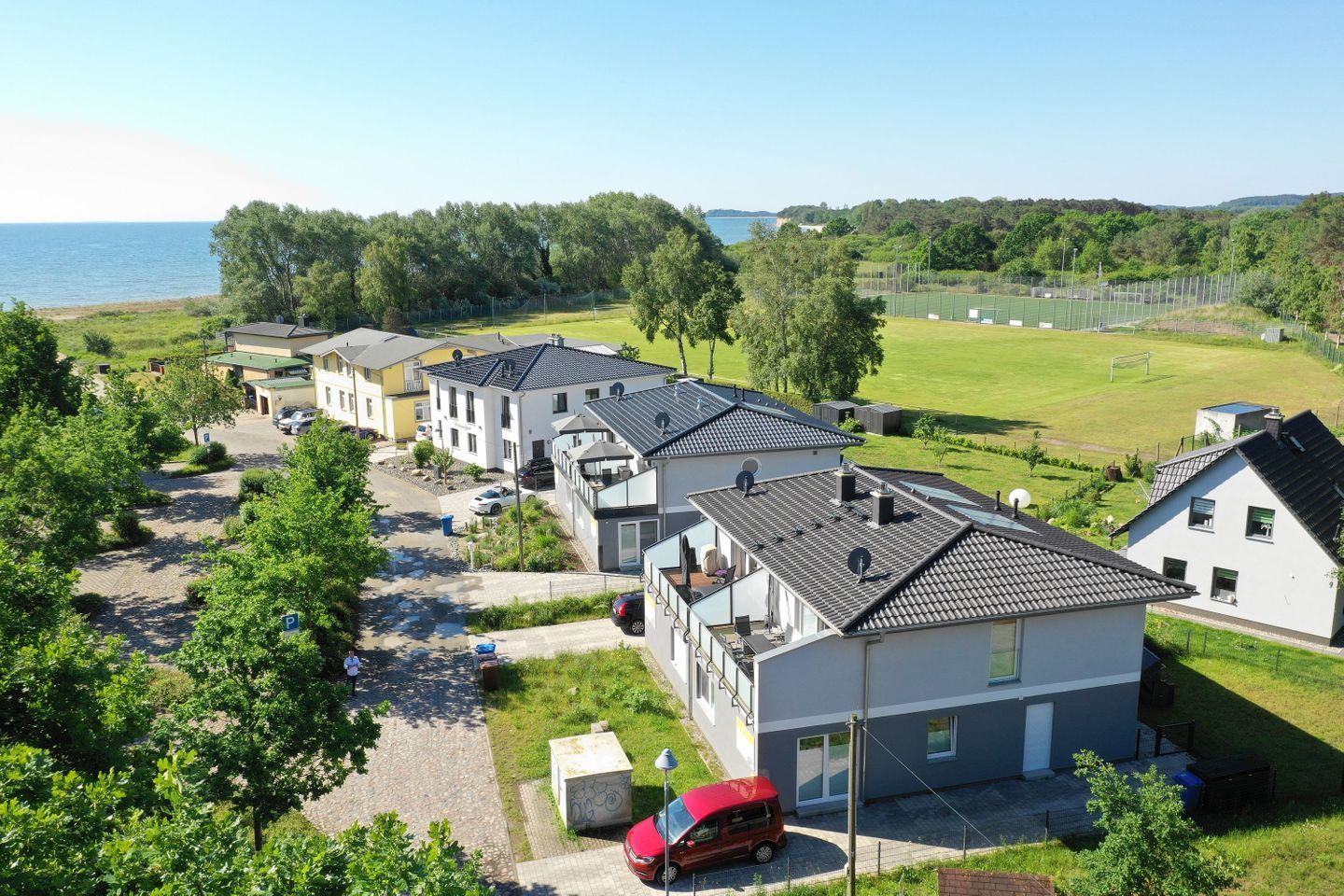 Un quartier résidentiel avec des maisons modernes, un espace de stationnement et une vue sur la mer.