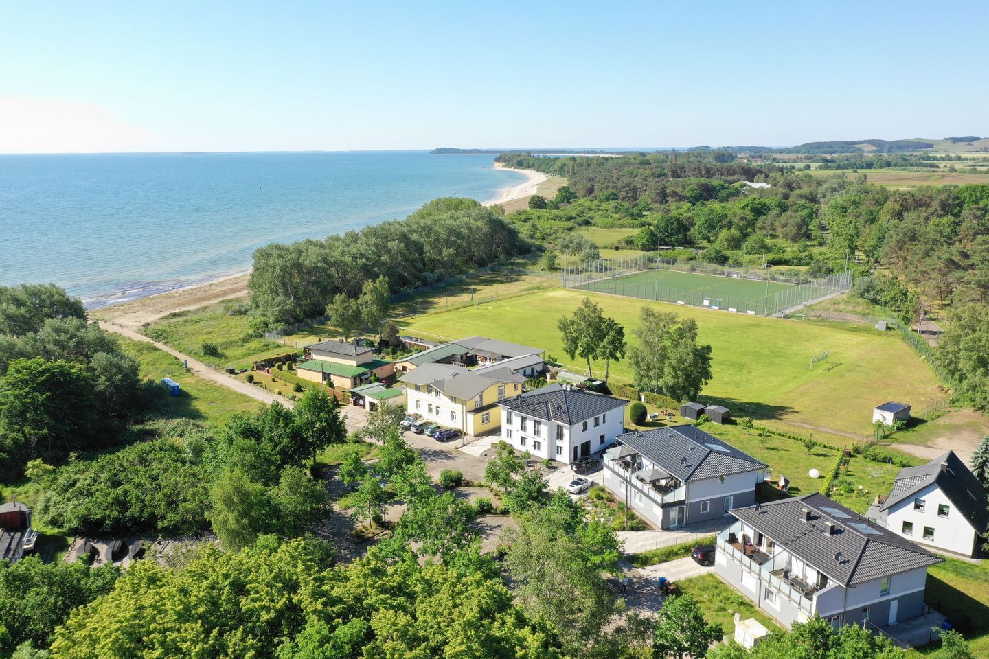 A residential area with houses, a beach, and a sports field.