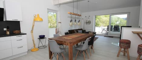 A modern kitchen with white cabinets, a wooden dining table, and a yellow floor lamp.