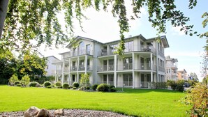 A multi-story hotel with balconies, a well-maintained lawn, and a gravel pathway. - Modern vacation apartment with private sauna and balcony - Villa Pauline FeWo 04 - (Göhren)
