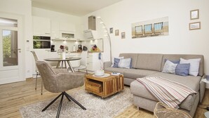 A modern living room with a sofa, coffee table, and dining area. - Modern vacation apartment with private sauna and balcony - Villa Pauline FeWo 04 - (Göhren)