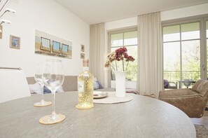 A round dining table with two wine glasses, a bottle, and a vase with flowers. - Modern vacation apartment with a private sauna and balcony - Villa Pauline FeWo 04 - (Göhren)