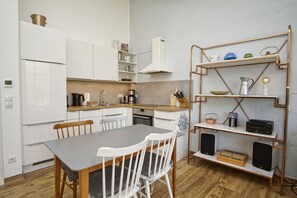 Eine moderne Küche mit weißen Schränken, einem Holztisch und einem Metallregal mit verschiedenen Küchenutensilien.