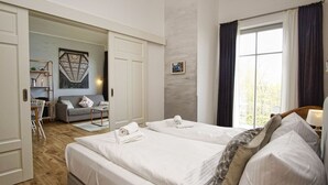 A hotel room with a large bed, a desk, a sofa, and a window with curtains. - Modern vacation apartment with private sauna and balcony - Villa Pauline FeWo 07 - (Göhren)