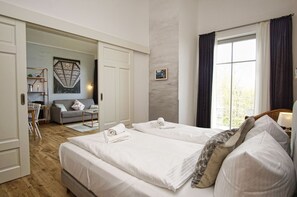 A hotel room with a large bed, a desk, a sofa, and a window with curtains. - Modern vacation apartment with private sauna and balcony - Villa Pauline FeWo 07 - (Göhren)