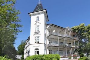 Ein weißes Gebäude mit einem Turm und mehreren Balkonen.