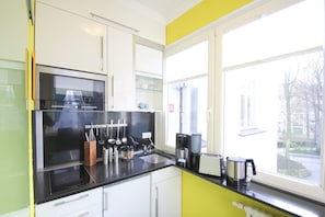 A modern kitchen with a black countertop, stainless steel appliances, and a window with a view of the outside. - Beachfront vacation apartment in a classic seaside style - Villa Stranddistel FeWo 3.6 (Binz)