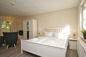 A bedroom with a bed, a wardrobe, a chair, and a desk with a lamp. - Ferienhaus Inselhus - small vacation home with garden and terrace - Holiday home (Glowe)
