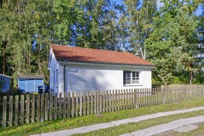 A small white house with a red-tiled roof, a wooden picket fence, and a clear blue sky in the background. - Inselhus Vacation Home - a small vacation home with a garden and terrace - Vacation Home (Glowe)