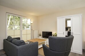 Una sala de estar moderna con un sofá, una mesa de centro, un televisor y un armario.