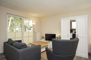 A modern living room with a sofa, a coffee table, a TV, and a wardrobe. - Inselhus Vacation Home - a small vacation home with a garden and terrace - Vacation Home (Glowe)