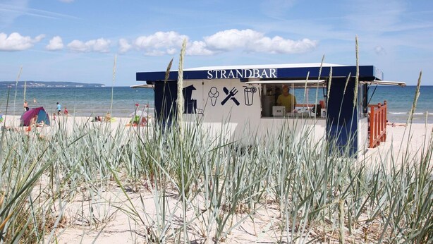 A beachside food kiosk named STRANDBAR with a clear view of the sea and beach in the background. - Dünenresort Binz - beachfront, chic vacation apartment with balcony directly in Binz - (Binz)