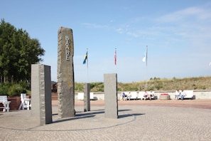 A stone monument with inscriptions, surrounded by a paved area with benches and flags. - Villa Wauzi - Carpe Diem Vacation Apartment at Villa Wauzi in Baabe (Baabe)