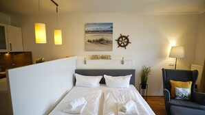 A hotel room with a bed, a chair, a desk, and a wall-mounted ship's wheel. - Terrace, free use of the AHOI adventure pool and sauna - Sea view apartment 30 - (Göhren)
