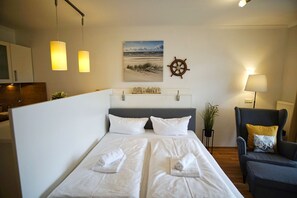 A hotel room with a bed, a chair, a desk, and a wall-mounted ship's wheel. - Terrace, free use of the AHOI adventure pool and sauna - Sea view apartment 30 - (Göhren)