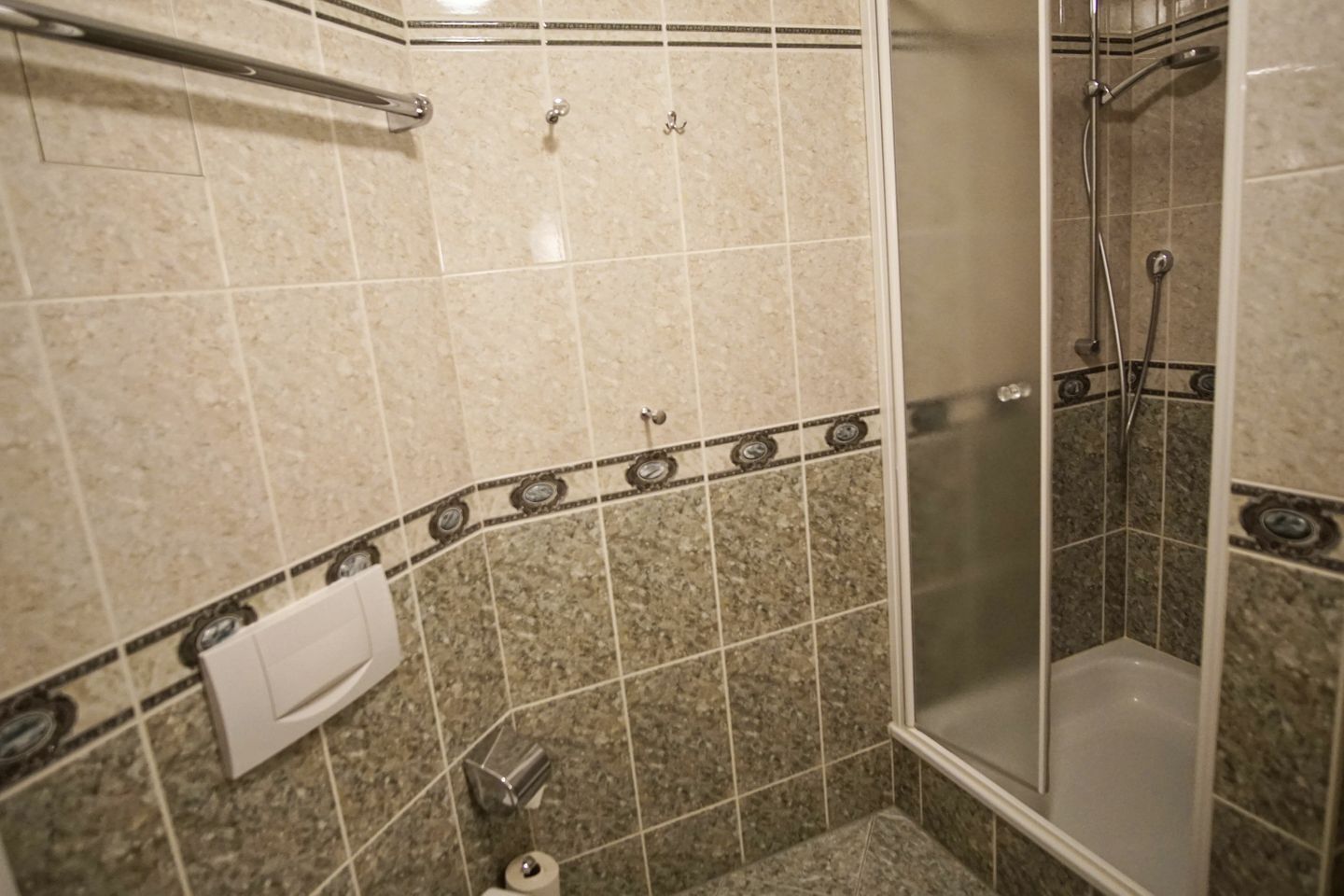 A bathroom with a shower, a toilet, and a towel rack.