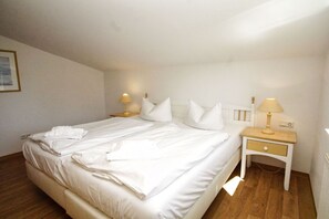 Ein Hotelzimmer mit einem ordentlich bezogenem Bett, zwei Nachttischen mit Lampen und einer Wandleuchte.