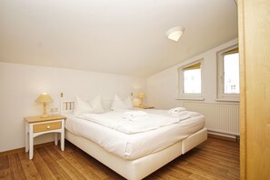Een slaapkamer met een bed, twee nachtkastjes, een raam en een radiator.