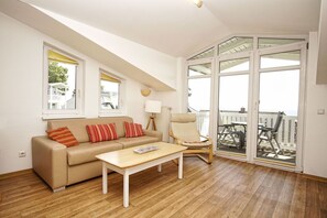 A modern living room with a sofa, a coffee table, a chair, and a balcony with a view.