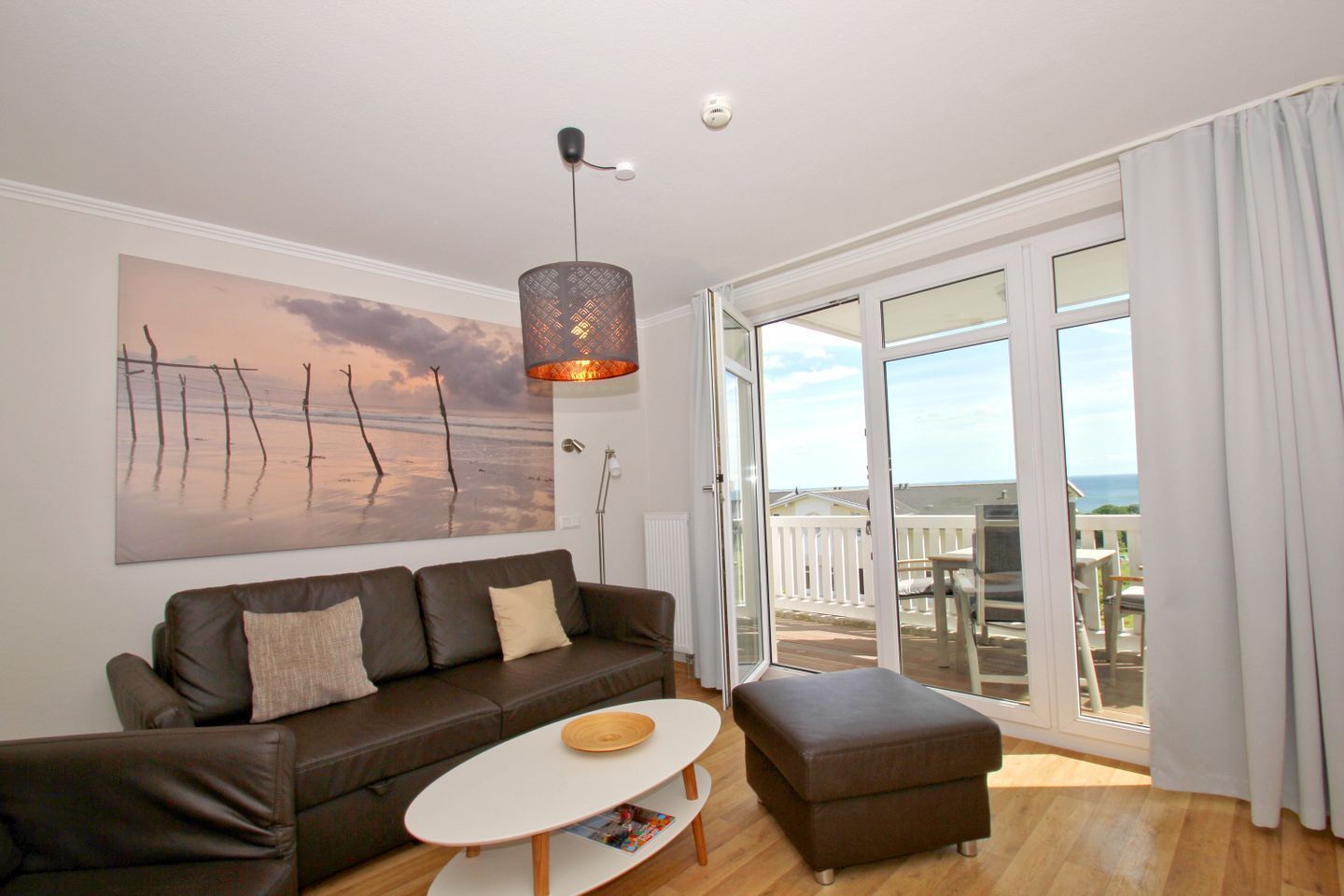 A modern living room with a large window, a brown leather sofa, a white coffee table, and a pendant light.
