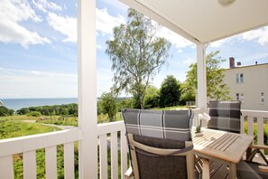 A covered outdoor seating area with a view of the sea and greenery. - With sea view and balcony, use of swimming pool and sauna - sea view apartment 26 - (Göhren)