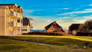 Un quartier résidentiel situé sur la côte, avec un immeuble d’appartements moderne et une maison traditionnelle.