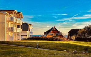 Uma área residencial à beira-mar, com um prédio de apartamentos moderno e uma casa tradicional.