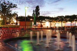 Un espace extérieur aménagé avec des chaises et des tables, une fontaine et un bâtiment en arrière-plan.