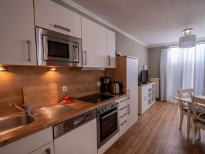 Une cuisine moderne dotée d’appareils électroménagers en acier inoxydable, de plans de travail en bois et d’un coin repas avec une table et des chaises.