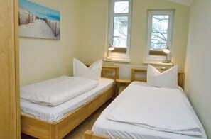 Ett litet, rent rum med två enkelsängar, ett element och ett fönster med utsikt över kala träd.