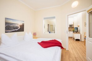 Ein Hotelzimmer mit einem Bett, einem Strandbild, einem Spiegel und einer Küchenzeile.