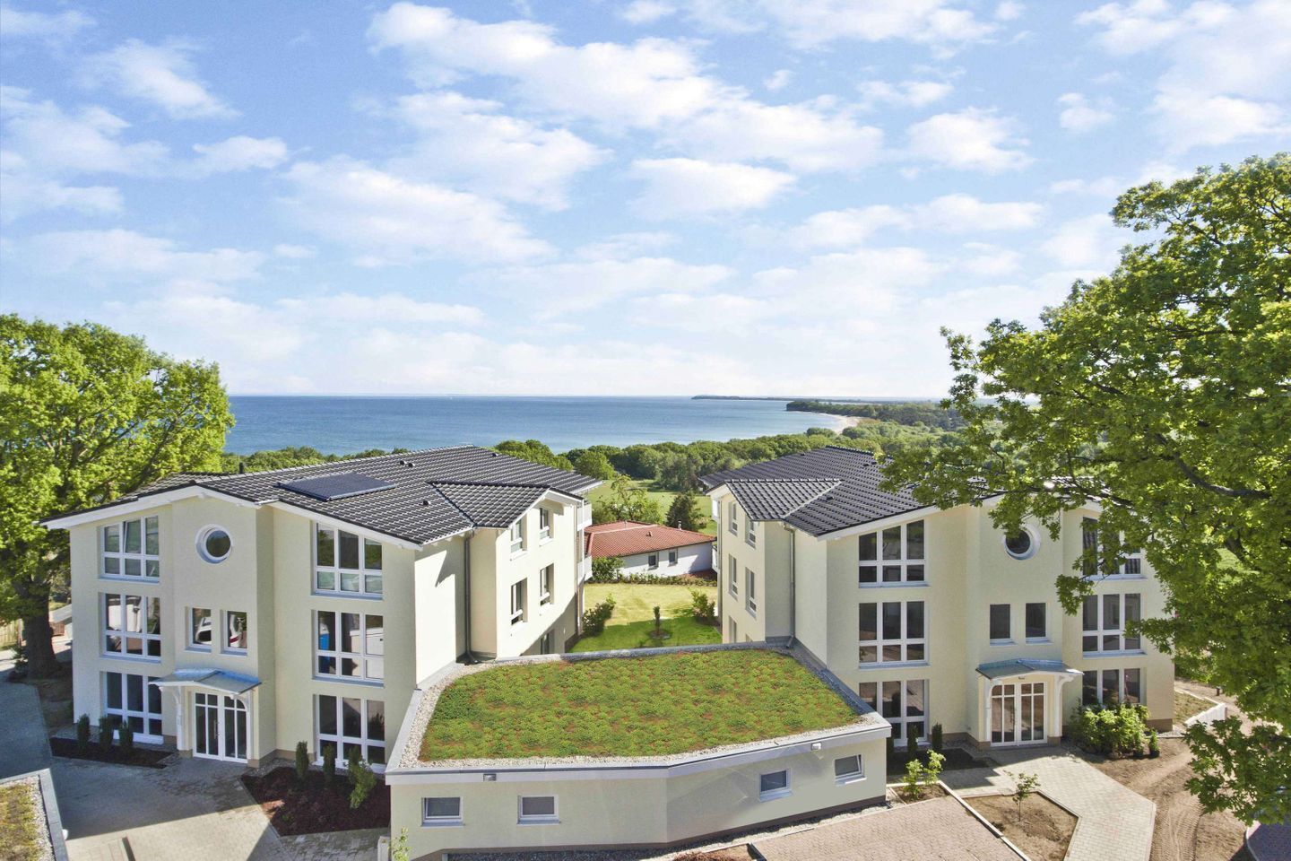 A modern building with multiple floors, a flat roof, and a view of the sea.