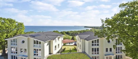 A modern building with multiple floors, a flat roof, and a view of the sea.