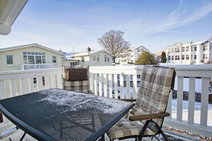 A balcony with a metal table and a plaid chair, overlooking a residential area with houses and a clear sky. - Vacation apartment no. 58 in the Meeresblick Residences - Meeresblick (Göhren)