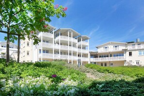 Un hotel de varios pisos con balcones, rodeado de exuberante vegetación y plantas florecientes.