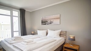 Hotellihuone, jossa on suuri sänky, kaksi yöpöytää, ikkuna verhoilla ja taulu seinällä.