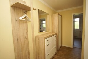 A hallway with a wooden wardrobe, a mirror, and a hanging garment. - Balcony, free use of the AHOI adventure pool and sauna - Apartment 56 with ocean view - (Göhren)