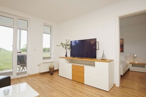 En moderne stue med et fladskærms-tv, et træskab og udsigt til det fri.