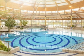 Ein innenliegender, kreisrunder Pool, umgeben von Liegestühlen und Pflanzen.