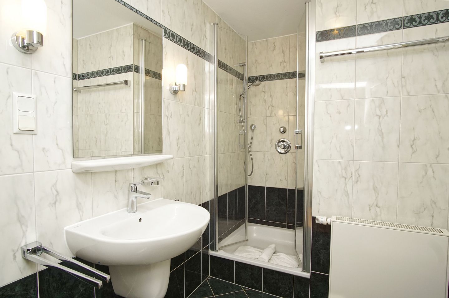 A bathroom with a white sink, a mirror, a shower enclosure, and a bathtub.