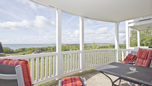 A covered outdoor deck with white railings, a table, and chairs with striped cushions. - With sea view and balcony, use of swimming pool and sauna - sea view apartment 14 - (Göhren)